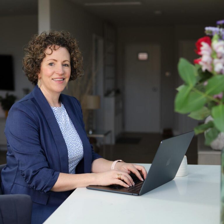 Laura Andrews blue jacket typing on laptop